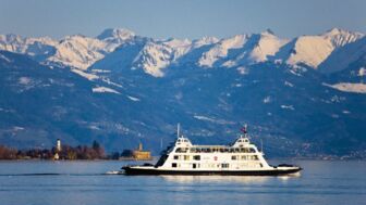 Ein Schiff fährt über den Bodensee mit der Bergwelt im Hintergrund