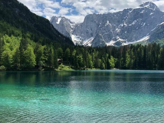 Ein türkisblauer See mit der Bergwelt der Julischen Alpen im Hintergrund auf der Mountainbikeroute durch Slowenien.