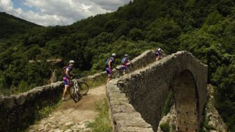 Mountainbiker*innen bei einer Brückenüberquerung in den Pyrenäen.