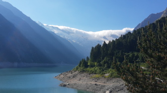 Ein Bergsee mit der umliegenden teilweise schneebedeckten Bergwelt.